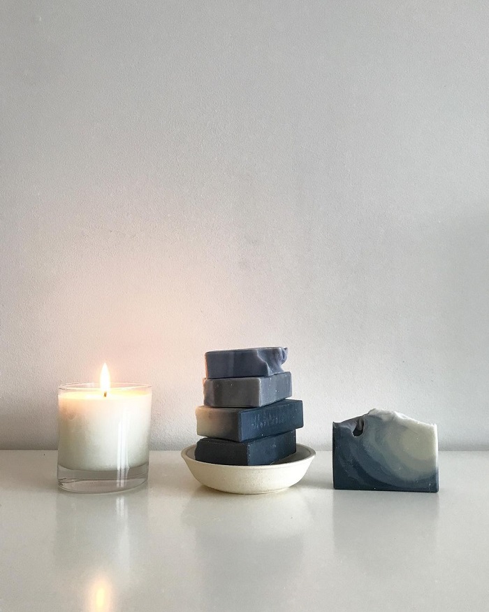 Dear
                Botanicals soap stacked next to a burning candle