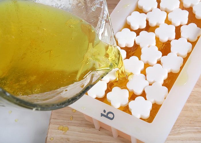 pouring orange melt and pour soap into a
mold | bramble berry