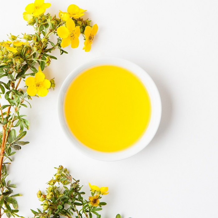 A bowl of oil surrounded by plants with
                yellow flowers